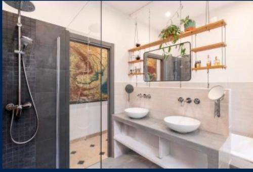 La salle de bains est pourvue d'une douche et de 2 lavabos blancs. dans l'établissement Villa Arson grand Appartement Art Deco, à Nice
