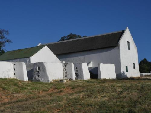 a white barn with a black roof on a field at The Old Village in Citrusdal