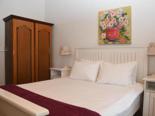 a bedroom with a white bed with a painting on the wall at The Old Village in Citrusdal