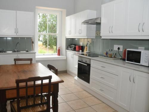 a kitchen with white cabinets and a table and a microwave at The Old Village in Citrusdal