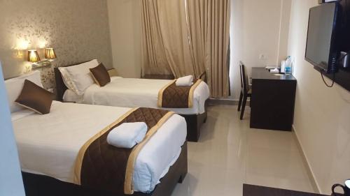 安加马尔伊Hotel Grand Regency, Angamaly的有两张床和一张书桌的酒店房间