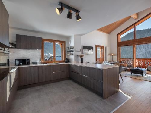 une cuisine avec des placards en bois et un salon dans l'établissement BO Immobilier - Apt PDS A306 - Châtel, à Châtel