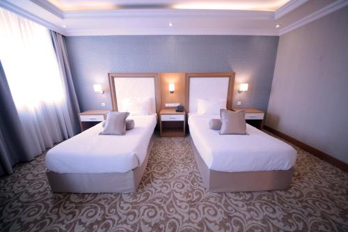 a hotel room with two beds and two windows at Momona Hotel in Addis Ababa