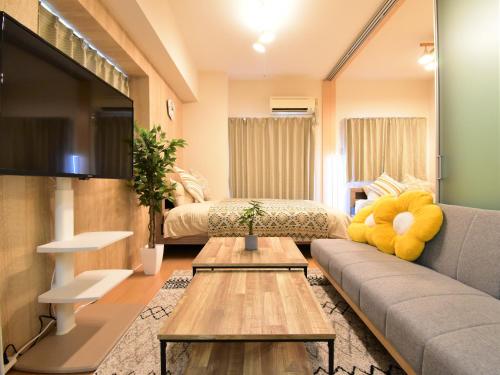 Una sala de estar con un sofá y un televisor. en Alphabed福山西桜町, en Fukuyama