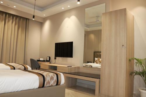 a bedroom with two beds and a tv on the wall at Infinity Stays Hotel Near Medanta Hospital in Gurgaon