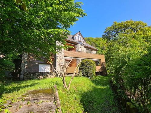 une maison en pierre avec un arbre dans la cour dans l'établissement Grand chalet équipé et calme avec parking à Cauterets - FR-1-812-124, à Cauterets