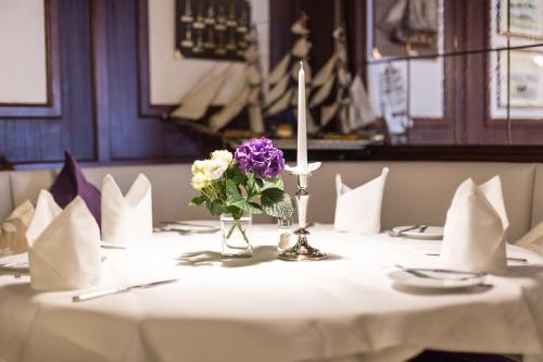 a table with a candle and flowers in a vase at Hotel-Restaurant Steuermann in Karlsruhe