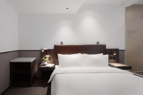 a bedroom with a large bed with white sheets and pillows at Mcsrh Hotel-Guiyang Xiaoshizi in Guiyang