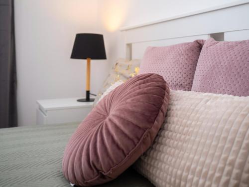 a bed with pink and white pillows on it at Írisz Apartman teljes ház in Balatonmáriafürdő