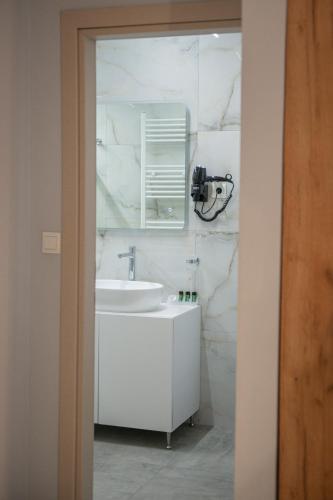 a white bathroom with a sink and a mirror at Alexandros in Giannitsa