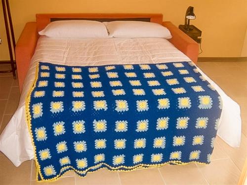 a bed with a blue and yellow blanket on it at Il Pergolato in Cannero Riviera
