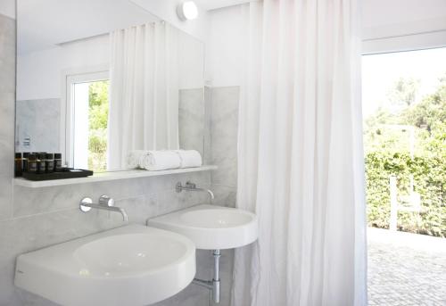 a white bathroom with a sink and a window at Quinta Do Miguel in Aldeia do Meco
