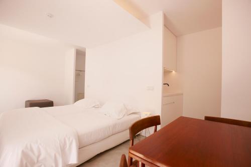 a bedroom with a white bed and a wooden table at Quinta Do Miguel in Aldeia do Meco