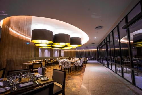 a dining room with tables and chairs and lights at Radisson Blu Okoume Palace Hotel, Libreville in Libreville