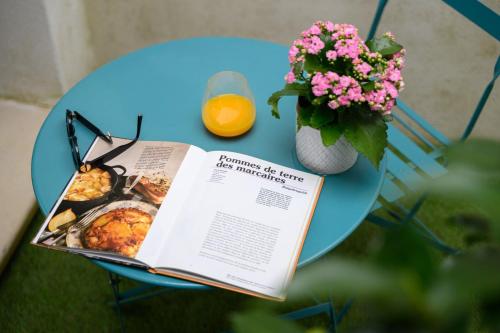 une table avec un livre et un vase de fleurs et de jus d'orange dans l'établissement OIQIA • Burdigala, à Bordeaux