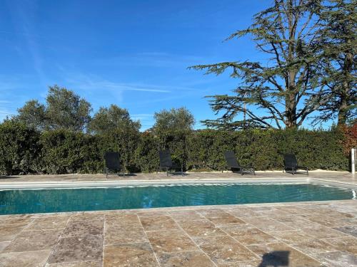 - une piscine avec des chaises et un arbre dans l'établissement Grande maison et piscine privée, à Saint-Ambroix