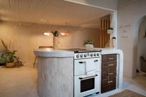 una cucina con piano cottura bianco e bancone di La Tête Penchée - Maison Duplex 2 Chambres et Jacuzzi a Deûlemont