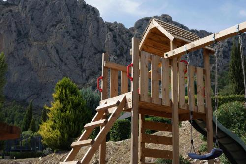 a wooden playground with a slide in front of a mountain at Torre de Arriba Casa Rural in Benimantell