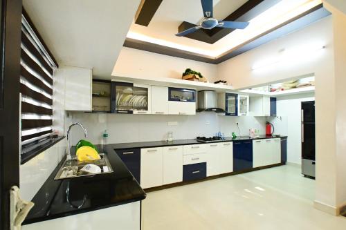a kitchen with white cabinets and a ceiling fan at San WAYANAD HOMESTAY AND SERVICE VILLA in Sultan Bathery