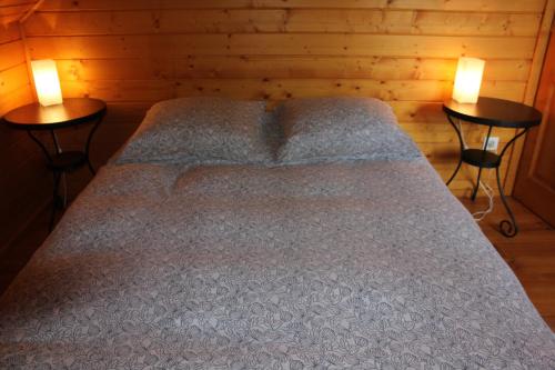 a bed in a wooden room with two tables at Le Chalet du Berger in Briançonnet