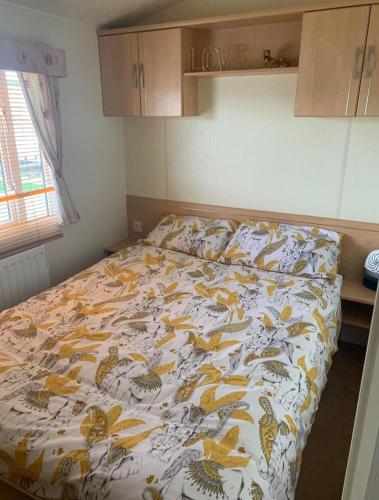 a bed in a bedroom with a bedspread with birds on it at 8 Berth 3 bed caravan Golden palm ML9 in Chapel Saint Leonards