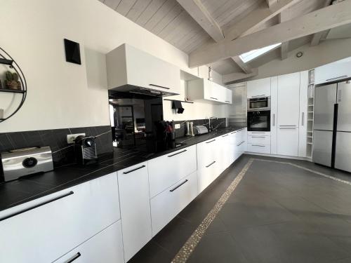 une cuisine avec des armoires blanches et des comptoirs noirs dans l'établissement RIVAGE Maison spacieuse avec piscine et spa, à Sainte-Marie de Ré