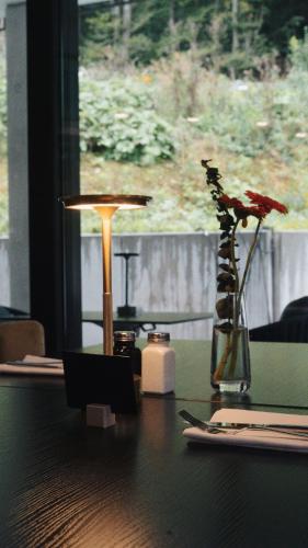 a table with a lamp and a vase with flowers on it at Boutique Hotel GreenLeaf in Sinzing