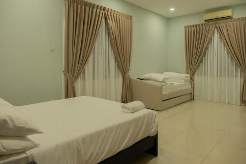 a bedroom with two beds and a chair in it at Ori Bali House Muar in Muar