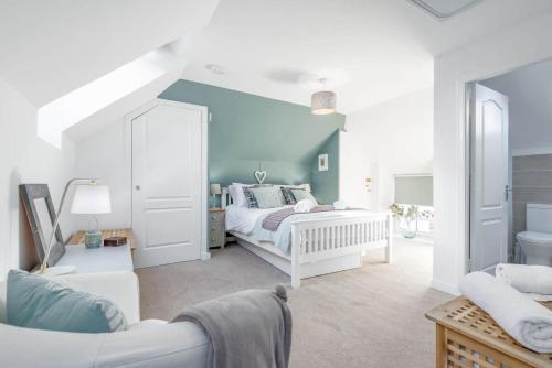 a bedroom with a white bed and a blue wall at Stoney Creek Cottage - Crail in Crail