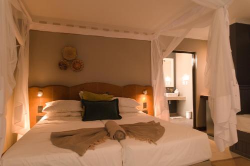 a bedroom with a white bed with a canopy at Toshari Lodge in Okaukuejo