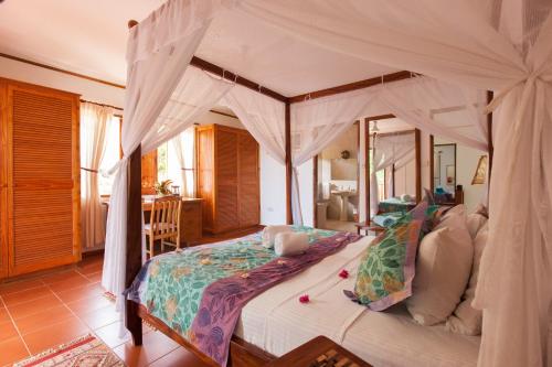 a bedroom with a large bed with a canopy at La Villa Mille Etoiles in Baie Sainte Anne
