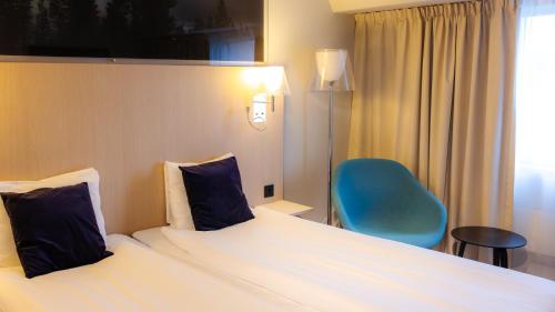 a hotel room with a bed and a blue chair at Quality Hotel Sundsvall in Sundsvall