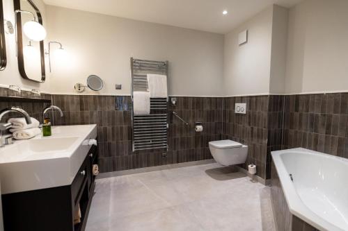 a bathroom with a sink and a toilet and a tub at Hotel Strandperle in Cuxhaven