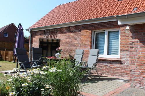 ostfriesisches Ferienhaus Anno 1899 في Großheide: منزل من الطوب مع كراسي وطاولة في الفناء