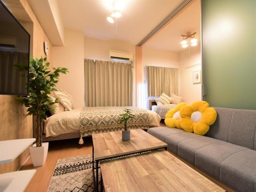 sala de estar con sofá y 2 camas en Alphabed福山西桜町, en Fukuyama