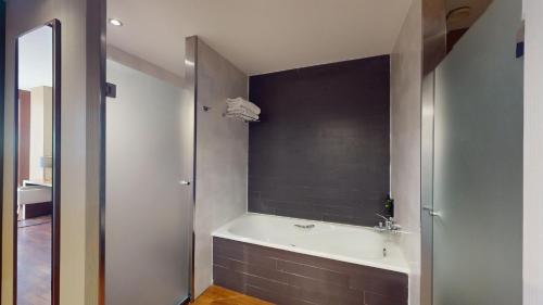 a bathroom with a bath tub and a sink at AZZ Valencia Congress Hotel & Spa in Paterna