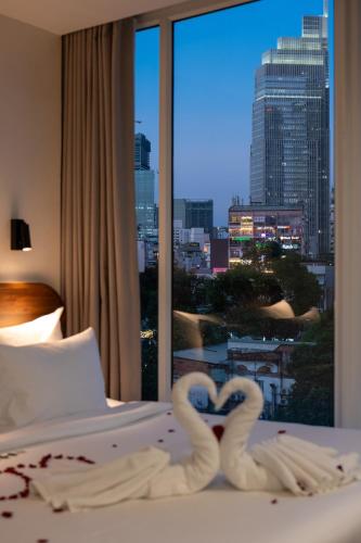 two swans making a heart on a bed in front of a window at Hato Saigon Boutique Hotel & Rooftop in Ho Chi Minh City