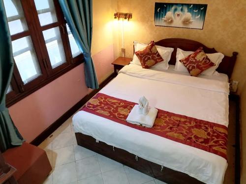 a bedroom with a bed with a towel on it at ShuYa Hotel 舒雅酒店 in Luang Prabang