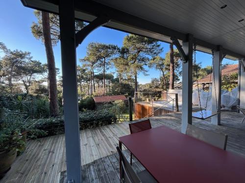une terrasse en bois avec une table rouge. dans l'établissement Villa Pyla sur Mer, à La Teste-de-Buch