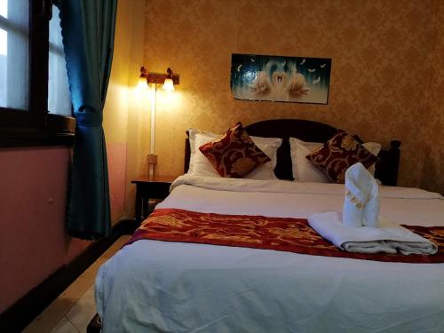 a hotel room with a bed with a towel on it at ShuYa Hotel 舒雅酒店 in Luang Prabang