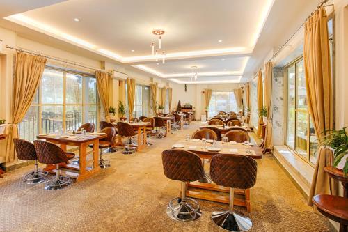 a restaurant with tables and chairs and windows at La Nicholas Lake View by Summit Hotels in Mawlyngkhung