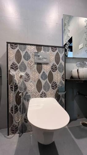 a bathroom with a white toilet and a tile wall at Luxe 2 BHK Apartment in Orchha