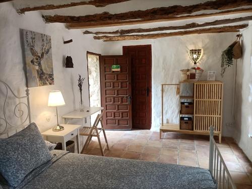 a bedroom with a bed and a table and a door at Torre de Arriba Casa Rural in Benimantell