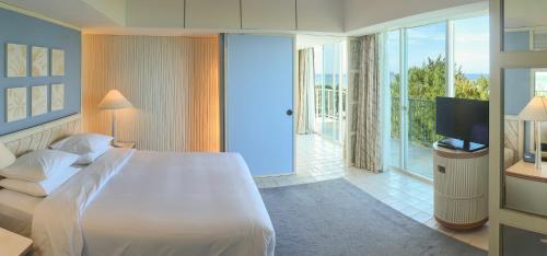 a bedroom with a large white bed and a television at Marianas Beach Resort in Saipan