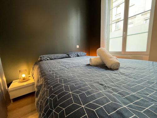 un lit dans une chambre avec une grande fenêtre dans l'établissement Cosy appartement au coeur des Chartrons et des quais, à Bordeaux