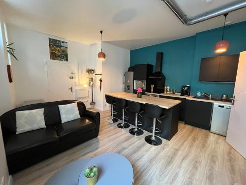 un salon avec un canapé noir et une cuisine dans l'établissement Cosy appartement au coeur des Chartrons et des quais, à Bordeaux