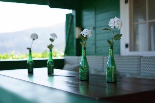 four green bottles with flowers in them sitting on a table at Torre de Arriba Casa Rural in Benimantell