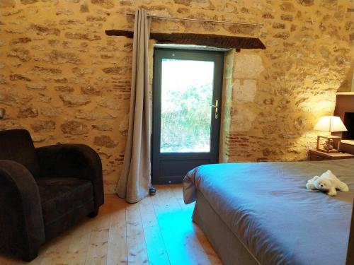une chambre avec un lit, une chaise et une fenêtre dans l'établissement la maison girafe, maison piscine, à Carsac-Aillac