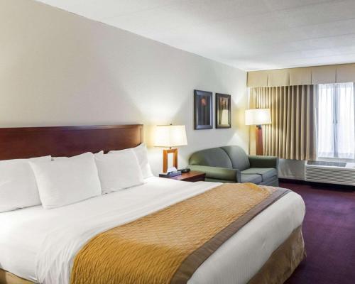 a hotel room with a large bed and a chair at Clarion Hotel Somerset - New Brunswick in Somerset