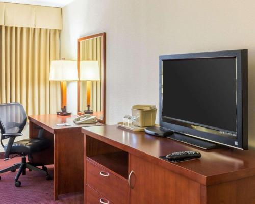 a hotel room with a television and a desk with a chair at Clarion Hotel Somerset - New Brunswick in Somerset